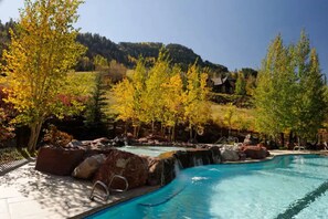 Relax by the serene pool surrounded by lush greenery and natural rock formations.