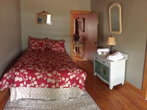Une chambre à coucher comprenant un lit, une commode, un miroir et une porte donnant sur une autre pièce.