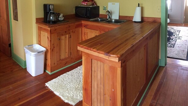 Eine Küche mit Holzschränken, einer Mikrowelle, einer Kaffeemaschine und einem Spülbecken.