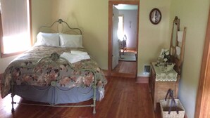 Ein Schlafzimmer mit Bett, Kommode, Spiegel und einer Tür zu einem anderen Raum.