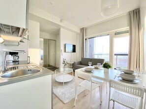 A modern kitchen with a sink, stove, and dining area with a table and chairs. - City Home Finland Ratina Panorama (Tampere)
