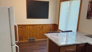 A kitchen with wooden cabinets, a marble countertop, and a blackboard on the wall. - Cozy Ranch (Rochester)