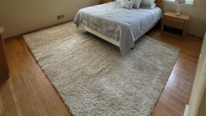 A bedroom with a bed, two bedside tables, a rug, and two windows with blinds. - Cozy Ranch (Rochester)