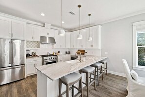 A modern kitchen with white cabinetry, stainless steel appliances, a marble island, and pendant lighting. - STEPS to Seacrest Restaurants, Shops, & More! Private Pool & Bikes! (Seacrest)