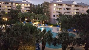 Ein Hotel mit mehreren Stockwerken, einem Schwimmbad und Außenbereichen mit Sitzgelegenheiten.