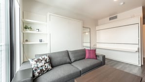 A modern living room with a grey sofa, a wooden coffee table, and built-in white storage units.