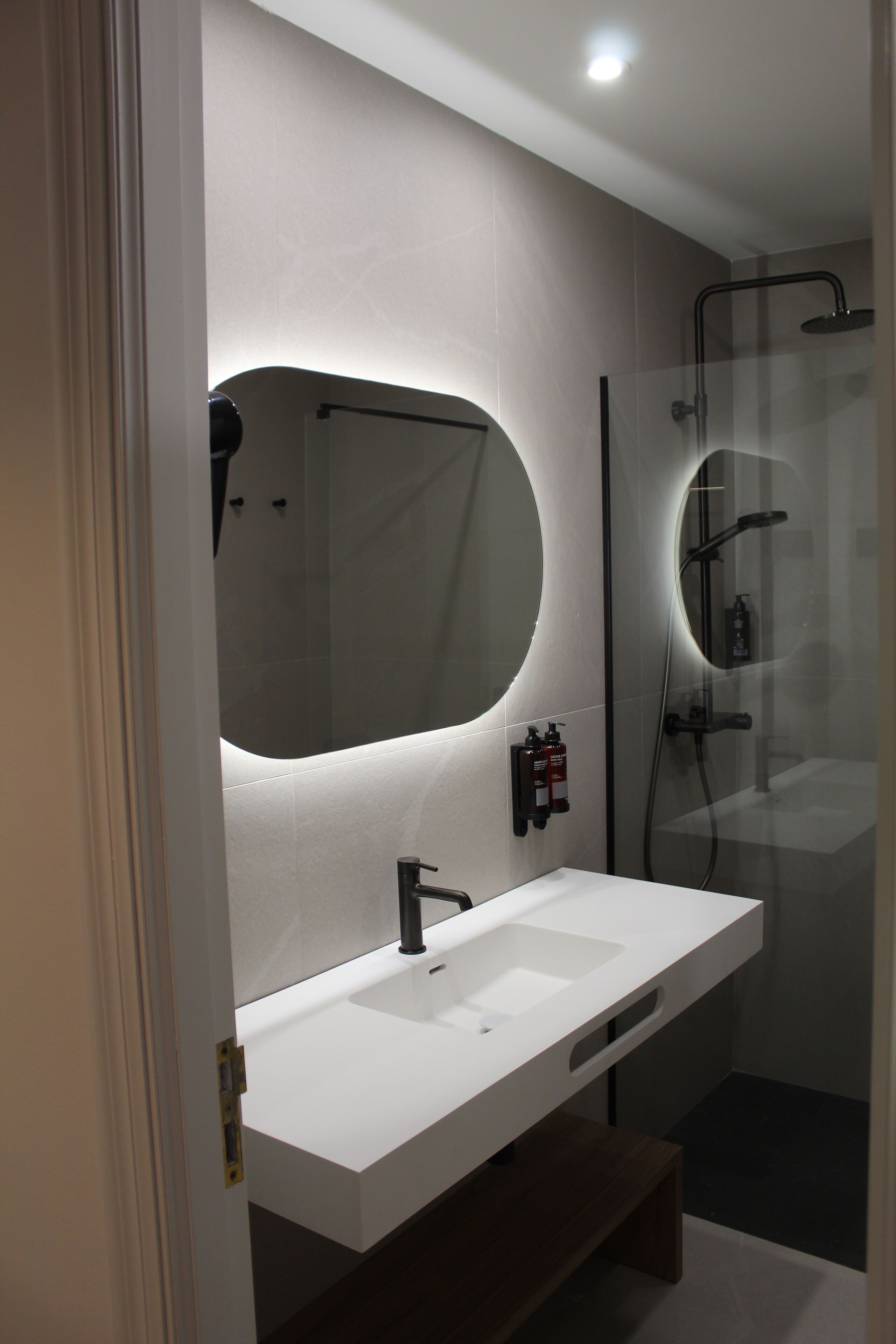 A modern bathroom with a white sink, a large mirror, and a glass-enclosed shower area.
