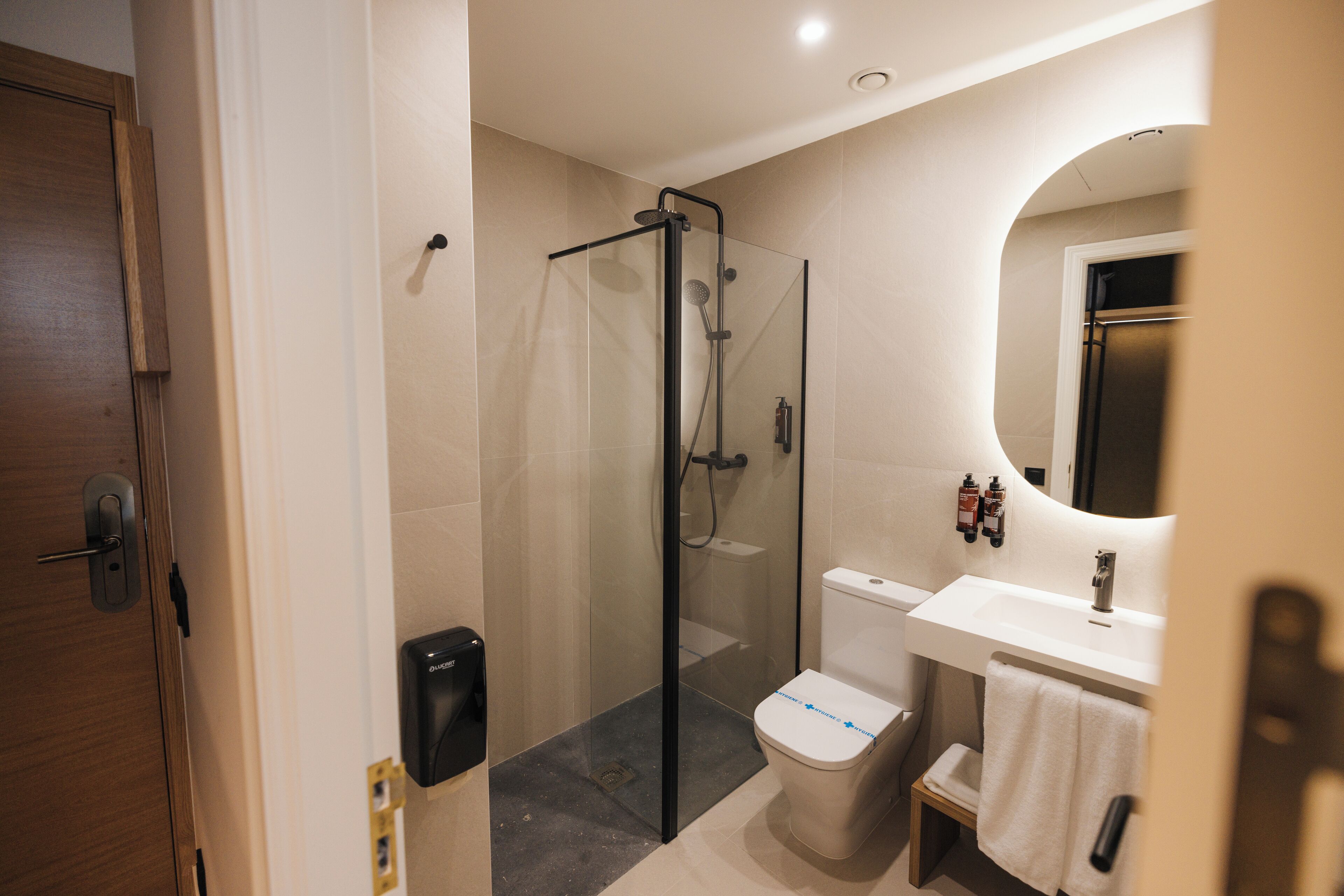 A modern bathroom with a glass-enclosed shower, a toilet, and a sink with a mirror.
