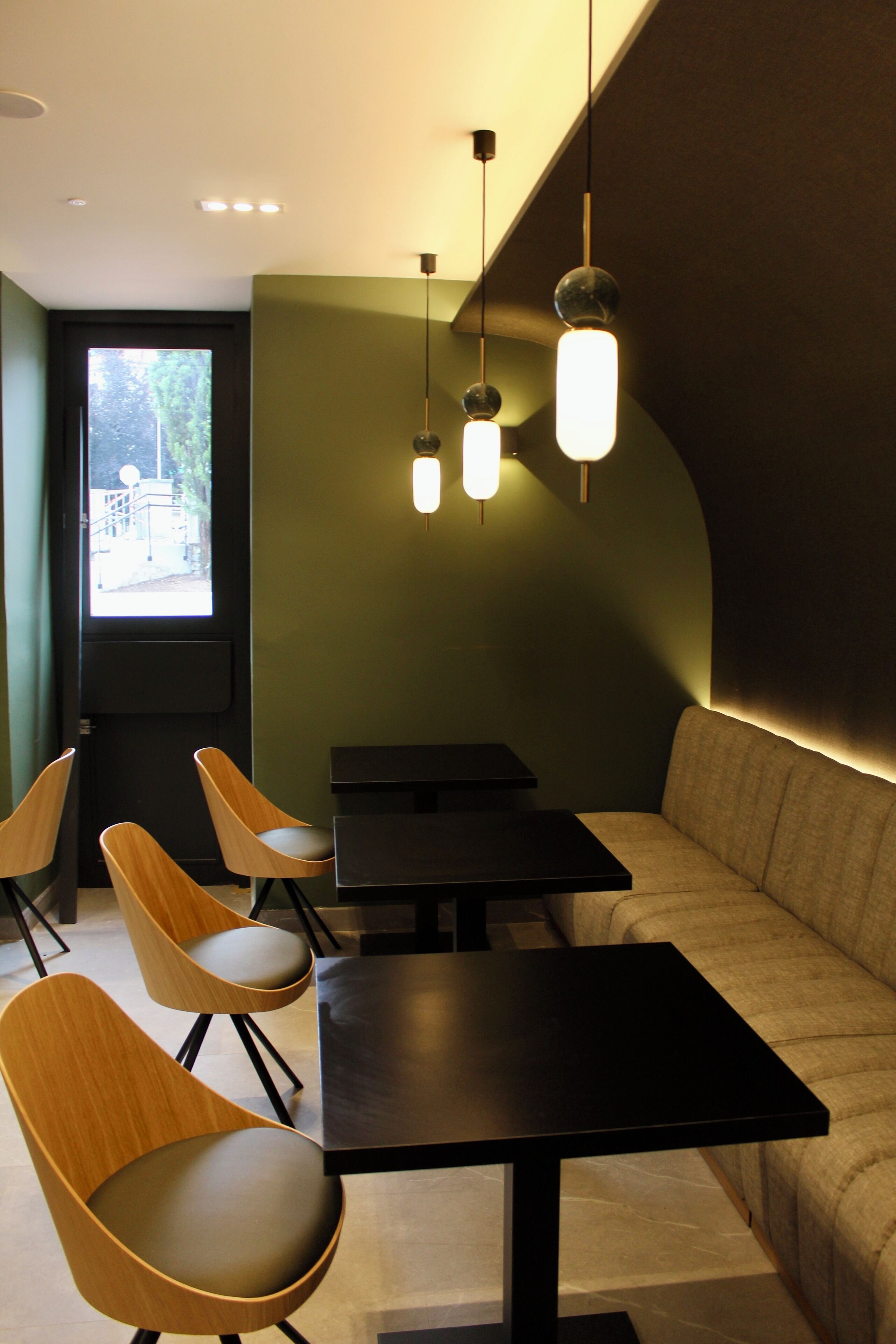 Un intérieur moderne avec des chaises en bois, des tables noires et un banc rembourré.