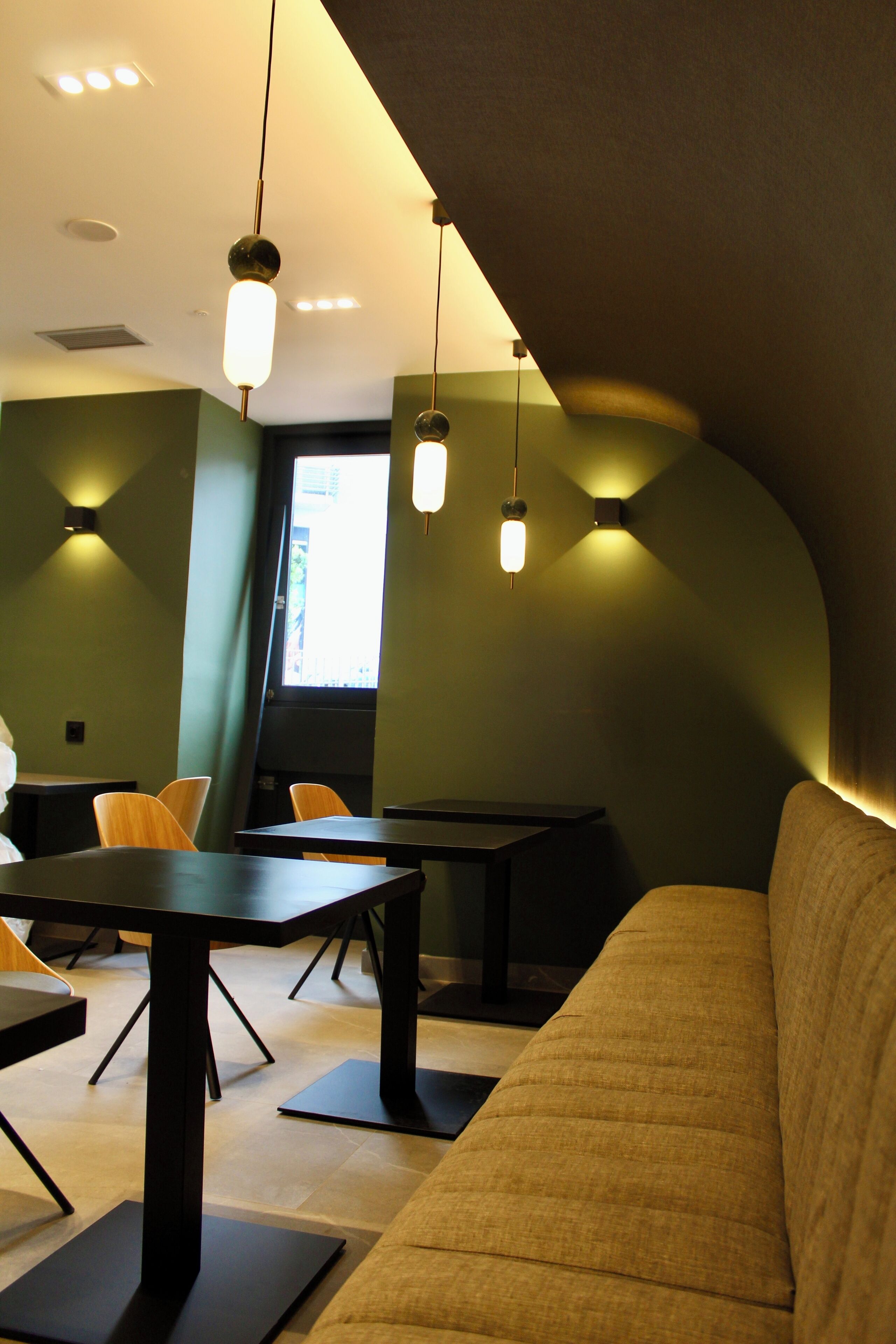 A modern interior with a sofa, tables, and chairs arranged for dining or socializing.