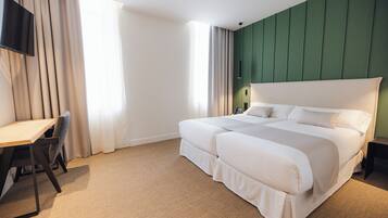 Une chambre d’hôtel avec un grand lit, un bureau et un téléviseur fixé au mur.