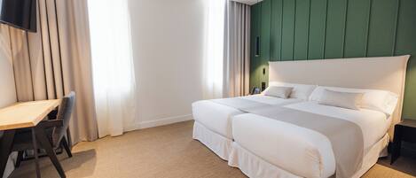 Una habitación de hotel con una cama grande, un escritorio y un televisor montado en la pared.