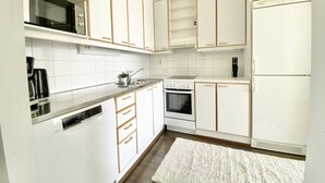 Eine moderne Küche mit weißen Schränken, einem eingebauten Backofen, einer Mikrowelle und einem Kühlschrank.