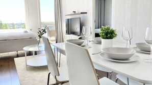 Ein modernes Hotelzimmer mit Essbereich, einem Bett, einem Fernseher und einem Balkon mit Aussicht.