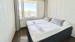 Ein Schlafzimmer mit einem großen Bett, Flussblick und einem Vorhangfenster.
