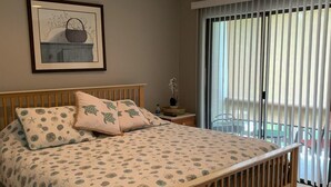 A bedroom with a bed, a ceiling fan, a nightstand, a framed picture, and a window with blinds. - Crystal River Condo -Near Three Sisters and Hunters Spring (Crystal River)