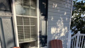 Deux fauteuils Adirondack en bois, placés sur une terrasse en bois, avec une maison en arrière-plan.