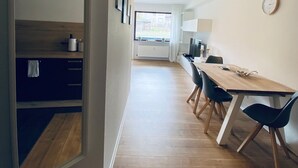 A modern kitchen with a wooden table and chairs, a view to the outside, and a clock on the wall. - Sunside vacation apartment in the heart of Winterberg (Winterberg)