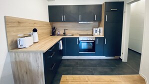 A modern kitchen with dark cabinets, a wooden countertop, a built-in oven, and a coffee maker. - Sunside vacation apartment in the heart of Winterberg (Winterberg)