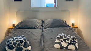 A bedroom with a bed, two bedside lamps, a window, and two wall-mounted paintings. - Sunside vacation apartment in the heart of Winterberg (Winterberg)