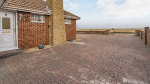 A brick house with a chimney, a paved driveway, and a view of the countryside. - Spacious property and stunning sea views in great location. (Greatstone)
