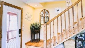 A wooden staircase with a handrail, a door with a glass panel, and a wall with a quote and a framed picture.