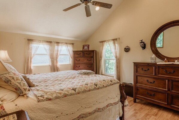 A bedroom with a bed, wooden dresser, and a ceiling fan.