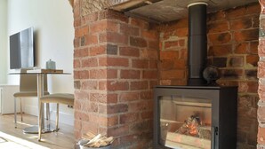 Una sala de estar moderna con chimenea de ladrillo, una mesa de vidrio y una silla.