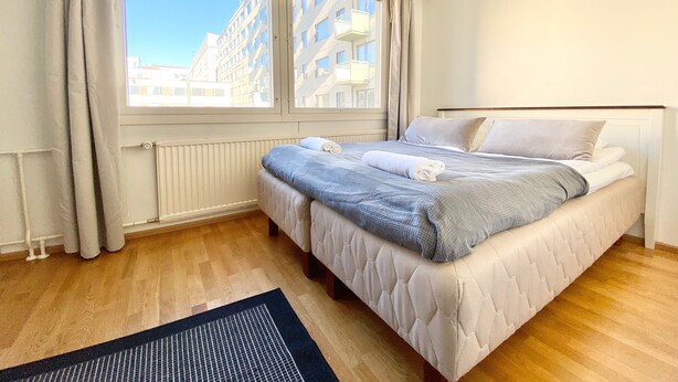 Ein Schlafzimmer mit großem Fenster, einem Bett mit Daunendecke und Kissen sowie Holzboden.