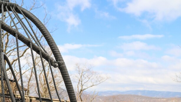 A wooden deck with a rope swing chair and a view of the mountains. - Cozy Cottage with beautiful Mountain View’s - close to wineries (Wintergreen Resort)