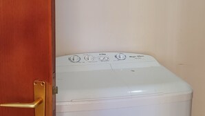 Una lavatrice bianca in una stanza con una porta di legno.