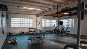 A gym with exercise equipment, a trampoline, and windows.