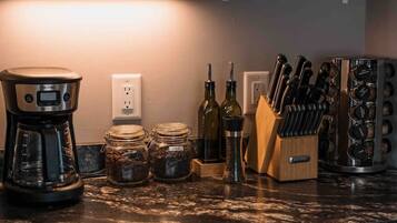 A kitchen with a coffee maker, jars, a knife block, and a countertop.