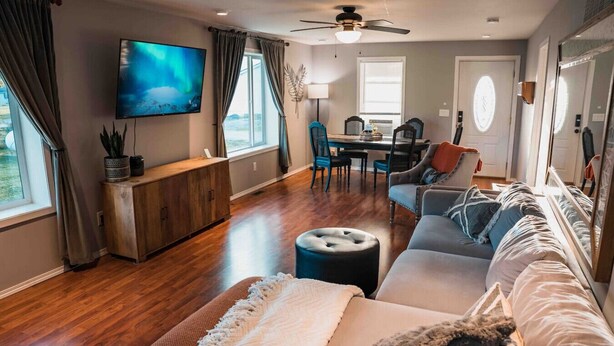 A living room with a sofa, ottoman, and a TV mounted on the wall.