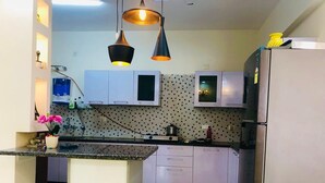 A modern kitchen with white cabinets, a black countertop, and a stainless steel refrigerator. - High-rise, Most Private, No Noise, Room & Common Areas (Ghaziabad)