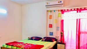 A bedroom with a bed, a nightstand, an air conditioner, a window with curtains, and a wall clock. - High-rise, Most Private, No Noise, Room & Common Areas (Ghaziabad)