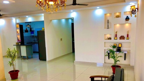 A modern living room with a glass coffee table, a sofa, and a dining area in the background. - High-rise, Most Private, No Noise, Room & Common Areas (Ghaziabad)