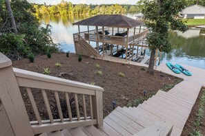 Una terraza de madera con un mirador que domina un lago, rodeado de árboles y un muelle.