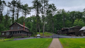 Eine Lodge mit einer zentralen Straße, umgeben von hohen Bäumen und einer Wiese.