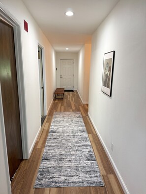 A hallway with wooden flooring, a gray rug, a bench, and a framed picture on the wall. - Beautiful Mountain Getaway with amazing views (Loch Lomond)
