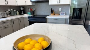 A kitchen with a marble countertop, a bowl of lemons, and modern appliances. - Beautiful Mountain Getaway with amazing views (Loch Lomond)