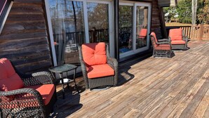 A wooden deck with wicker furniture and glass doors.