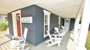 Eine Veranda mit weißen Schaukelstühlen und einem Schild mit der Aufschrift 'Welcome to Our Place'.