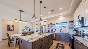 A modern kitchen with a large island, dark wood cabinets, stainless steel appliances, and pendant lighting. - Kanab Getaway Red Mesa Ranch, Near Zion, Amazing Red Rock & Starry Night Views! (Kanab ( Will Show as Canyon City on Some Apps))