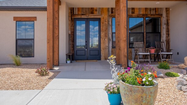 A modern building with a wooden facade, a black double door, and a patio area with outdoor seating. - Kanab Getaway Red Mesa Ranch, Near Zion, Amazing Red Rock & Starry Night Views! (Kanab ( Will Show as Canyon City on Some Apps))