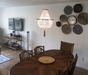 A dining area with a wooden table, chairs, a chandelier, and decorative plates on the wall.