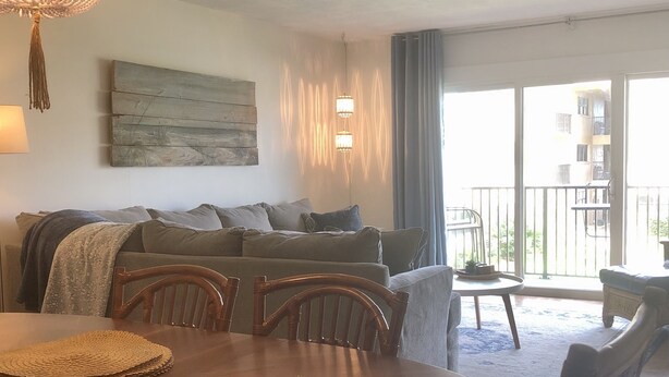 Un coin repas avec une table ronde, des chaises et un lustre. On y trouve également un ensemble de canapés et un luminaire fixé au mur.