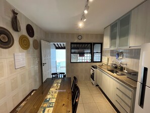 Uma cozinha moderna com mesa de jantar de madeira, eletrodomésticos embutidos e pratos decorativos na parede.