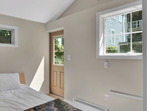 A bedroom with a bed, a window, and a door leading outside. - Two-bedroom Hideaway in Downtown Newport! (Newport)