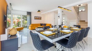 A modern dining area with a glass table, black chairs, and a yellow sofa in the background. - Modern villa MODERNA with heated pool, hot tub and sauna (Malinska)